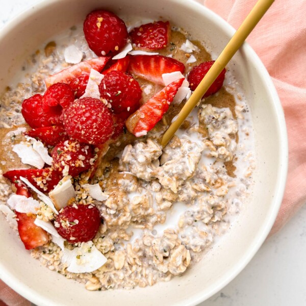 bowl of vanilla overnights oats with cashew milk, berries and coconut flakes on top