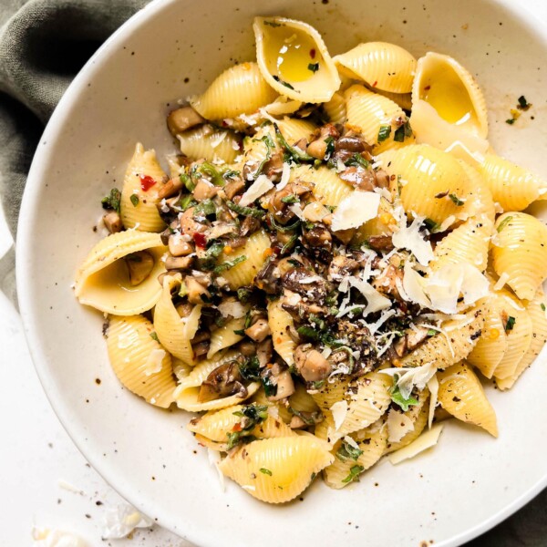 pasta in a beige bowl on a green linen cloth