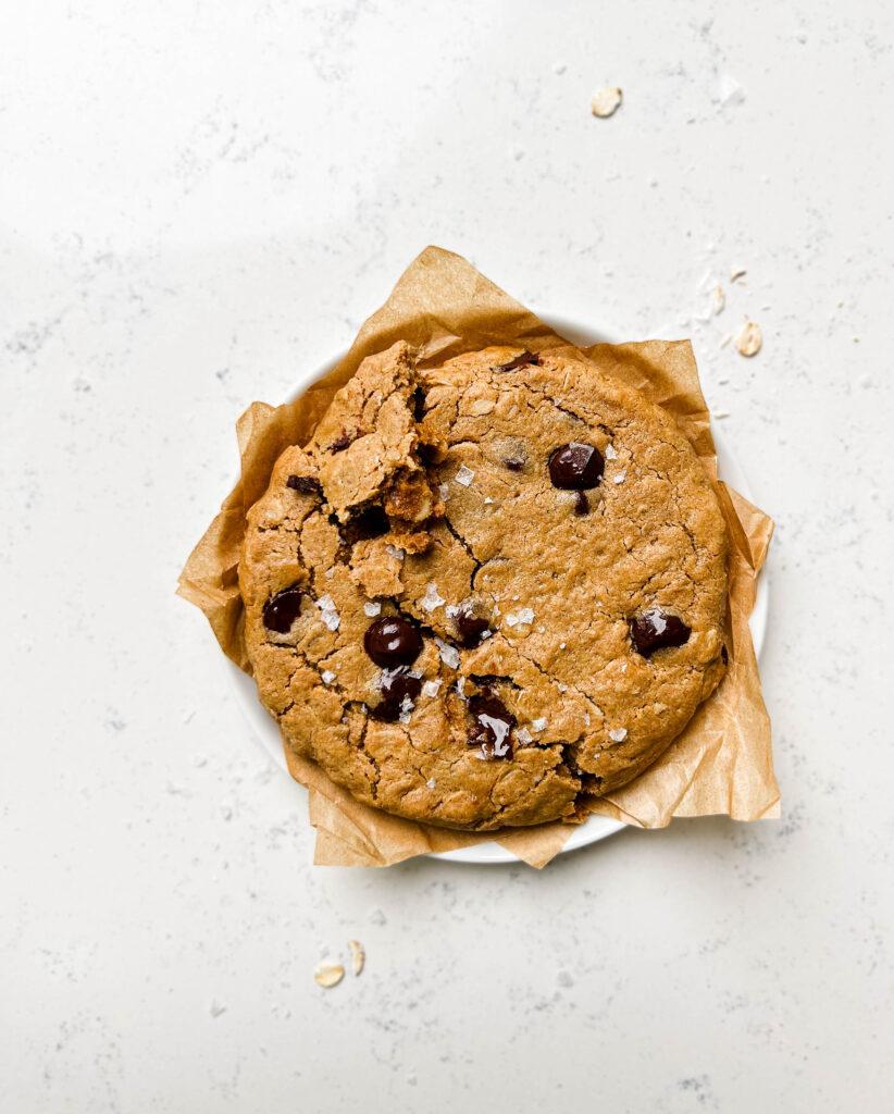 single-serve oatmeal chocolate chip cookie on a white plate with brown parchment paper