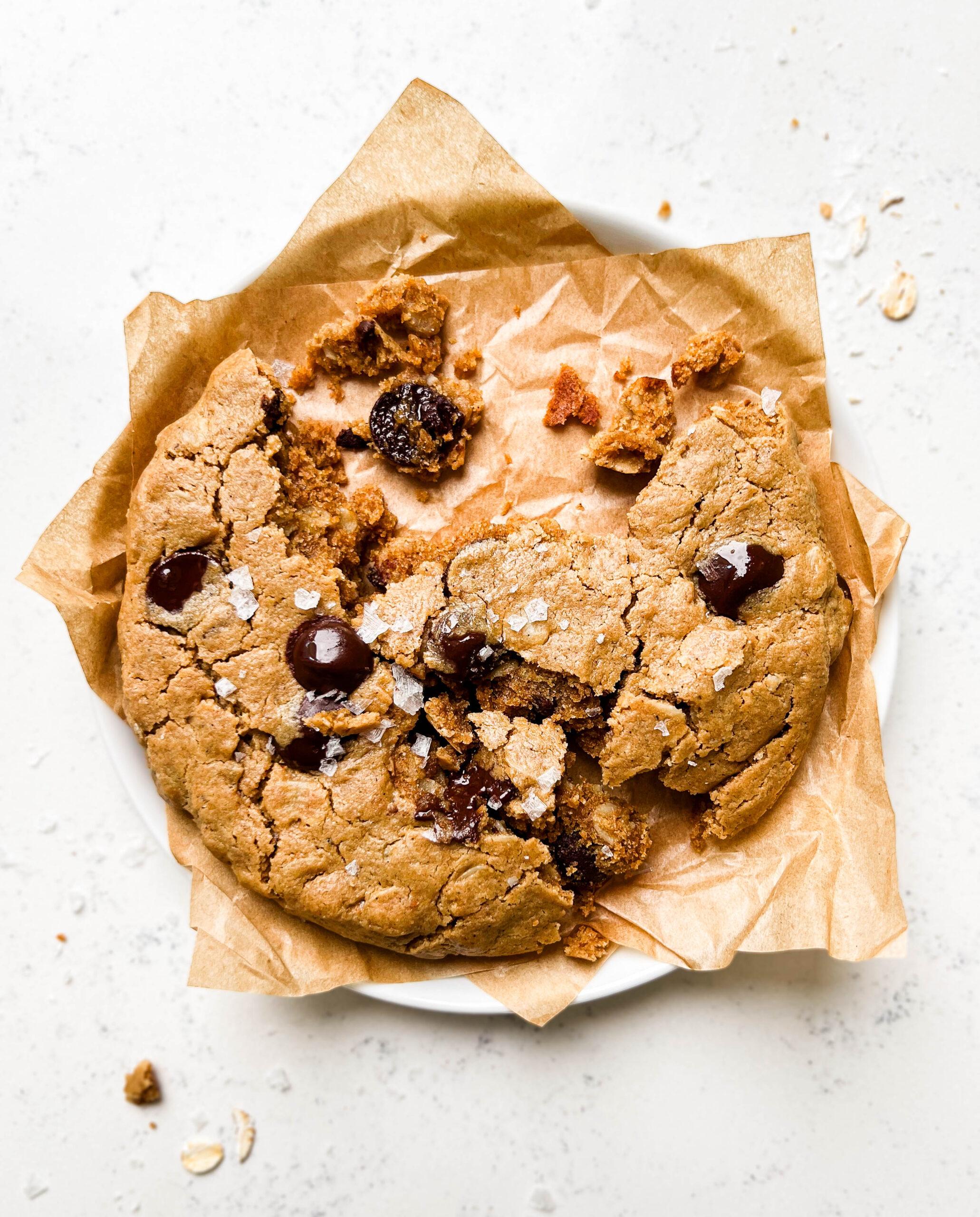 single-serve oatmeal chocolate chip cookie on a white plate with brown parchment paper