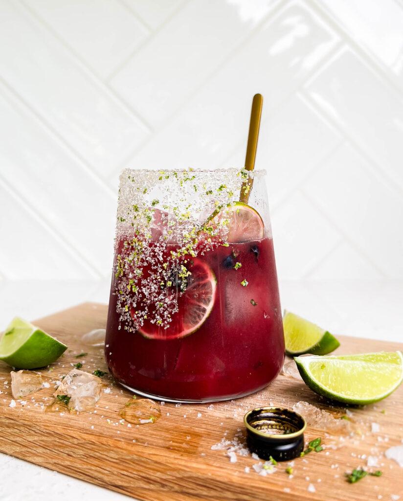 summer berry smash mocktail on cutting board with lime wedges