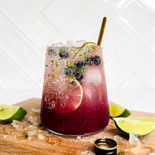 summer berry smash mocktail on cutting board with lime wedges