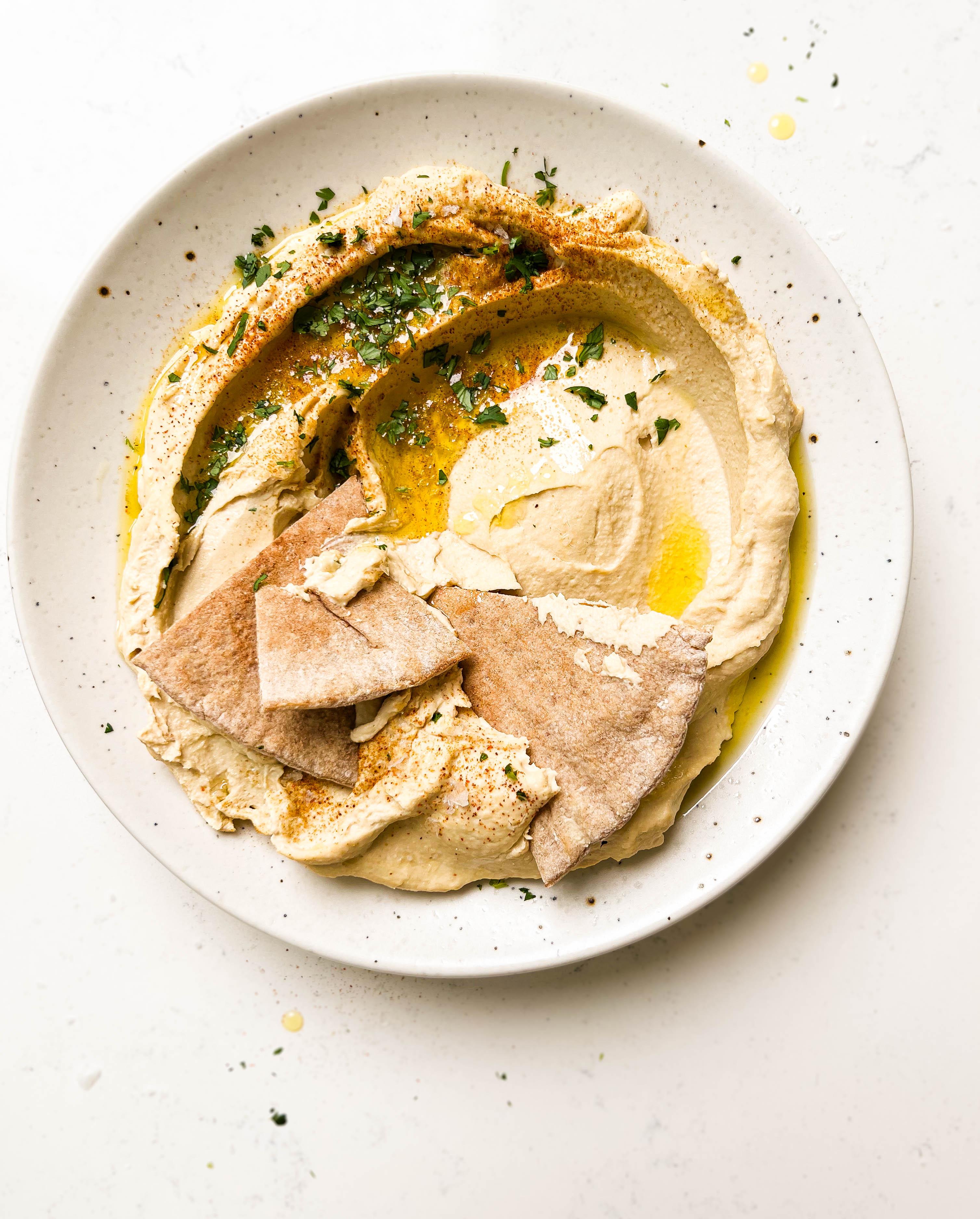 homemade hummus on a speckled plate with pita bread