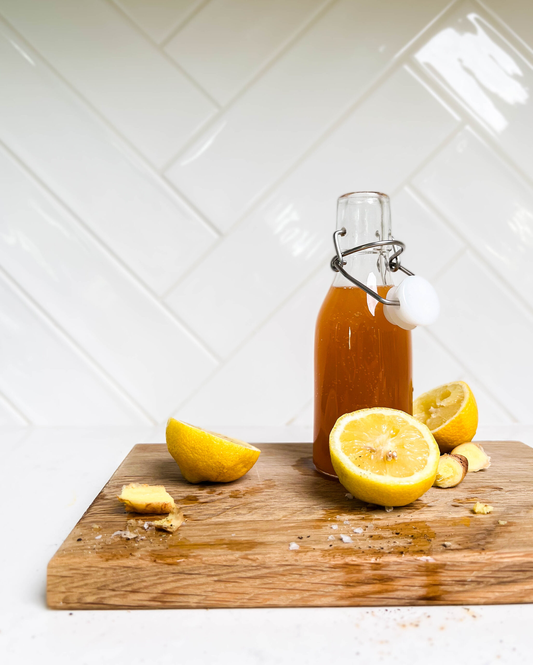 cutting board with lemon and glass bottle on top