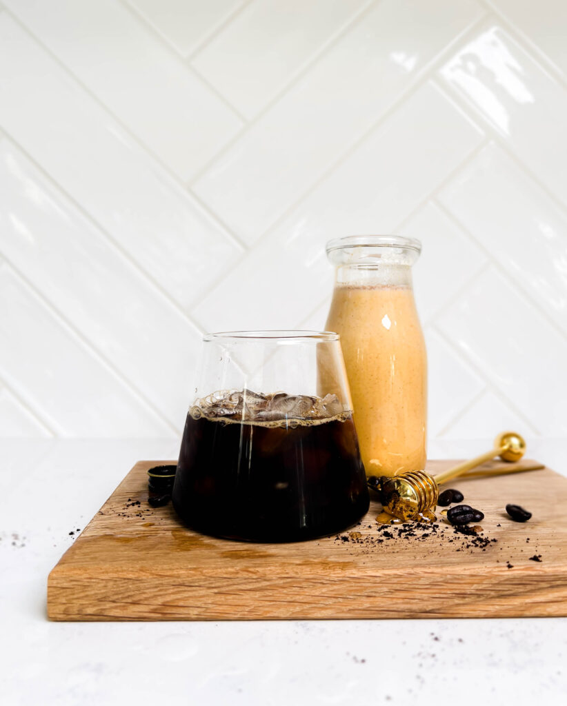 iced espresso and pumpkin spice creamer on a wooden cutting board
