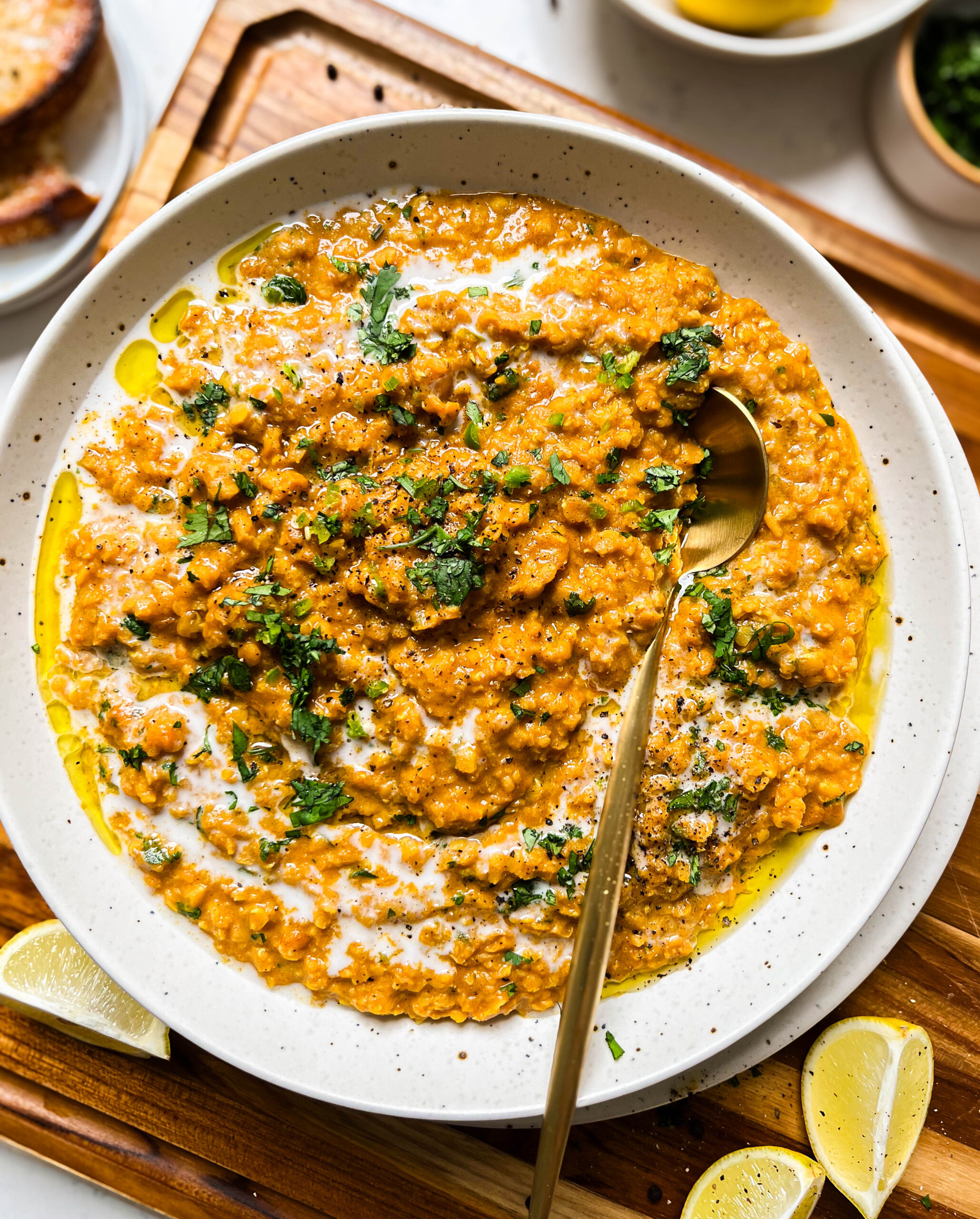 bowl of red lentil curry on a wood cutting board