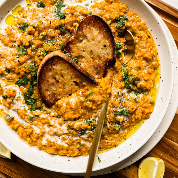 bowl of red lentil curry on a wood cutting board