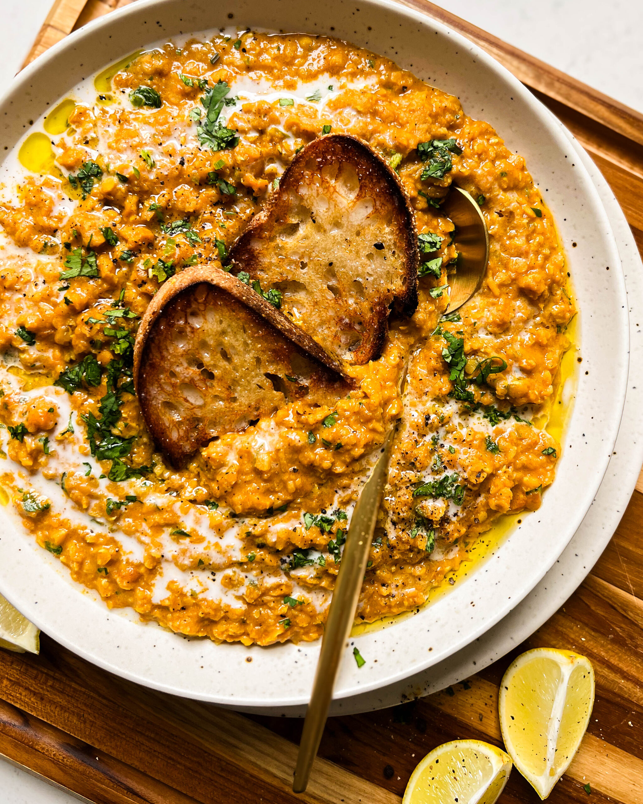 bowl of red lentil curry on a wood cutting board