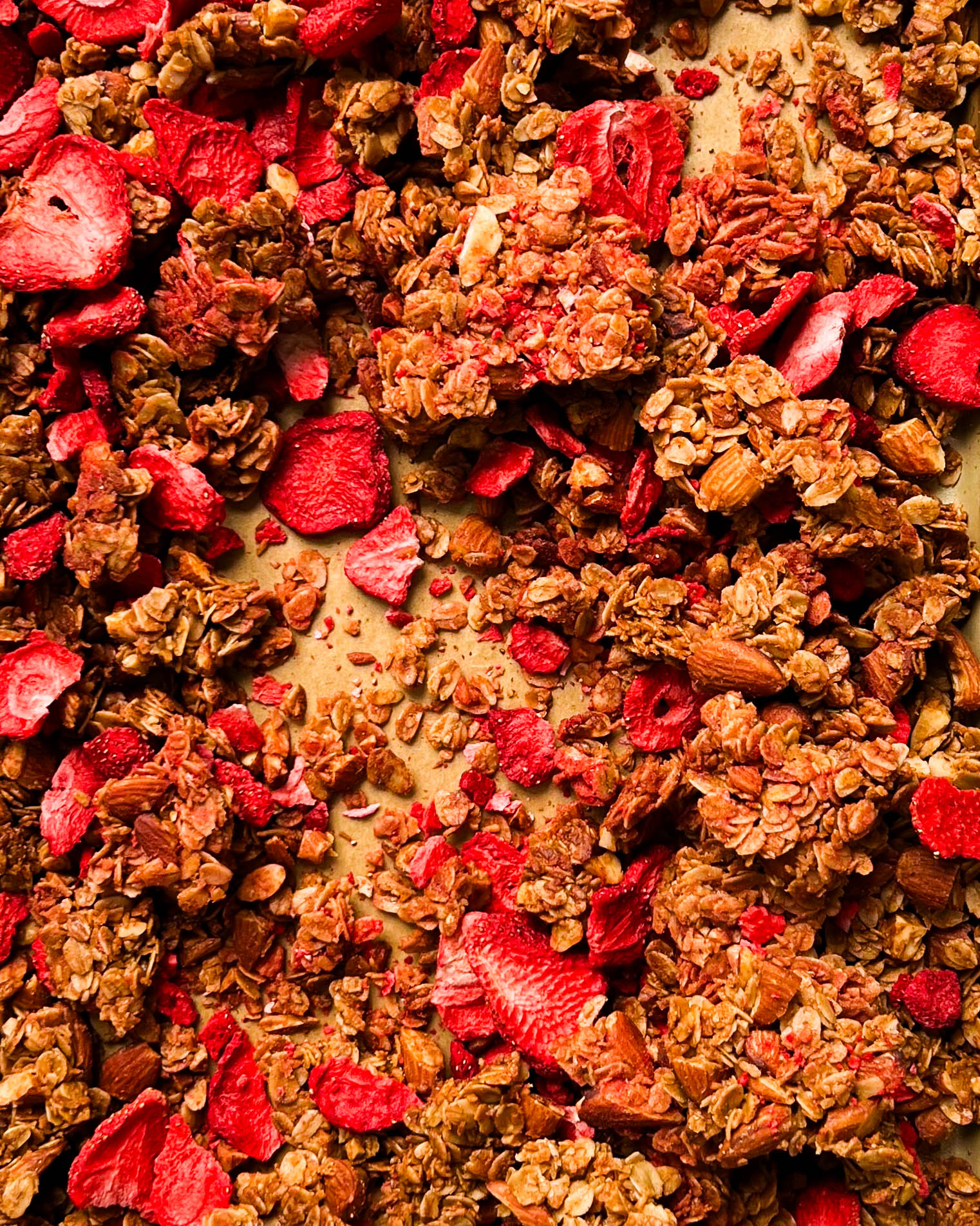 strawberry almond granola on a gold sheet pan