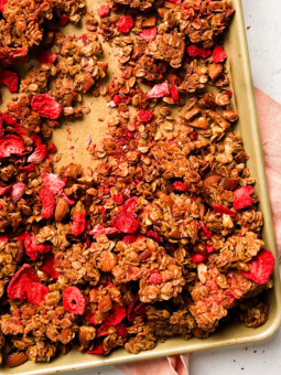 strawberry almond granola on a gold sheet pan