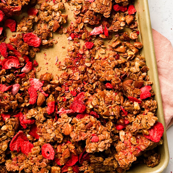 strawberry almond granola on a gold sheet pan