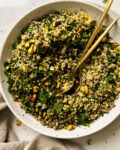 bulgur salad in a bowl with two gold spoons