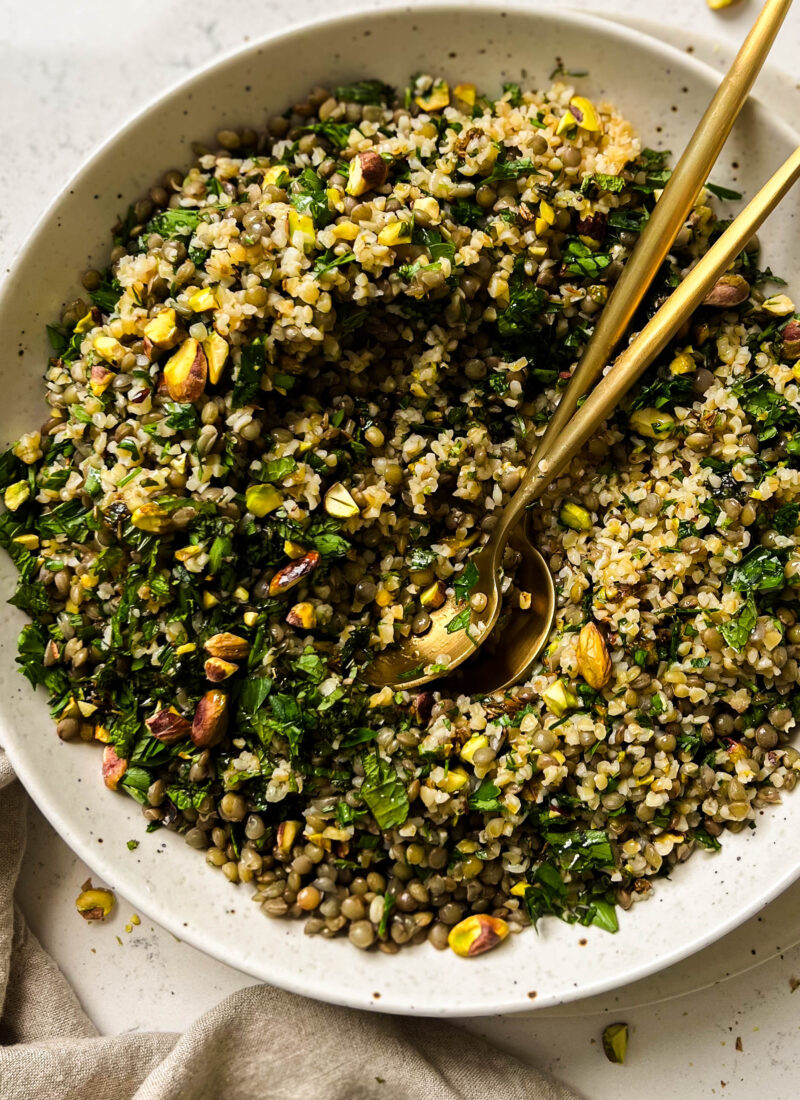 bulgur salad in a bowl with two gold spoons