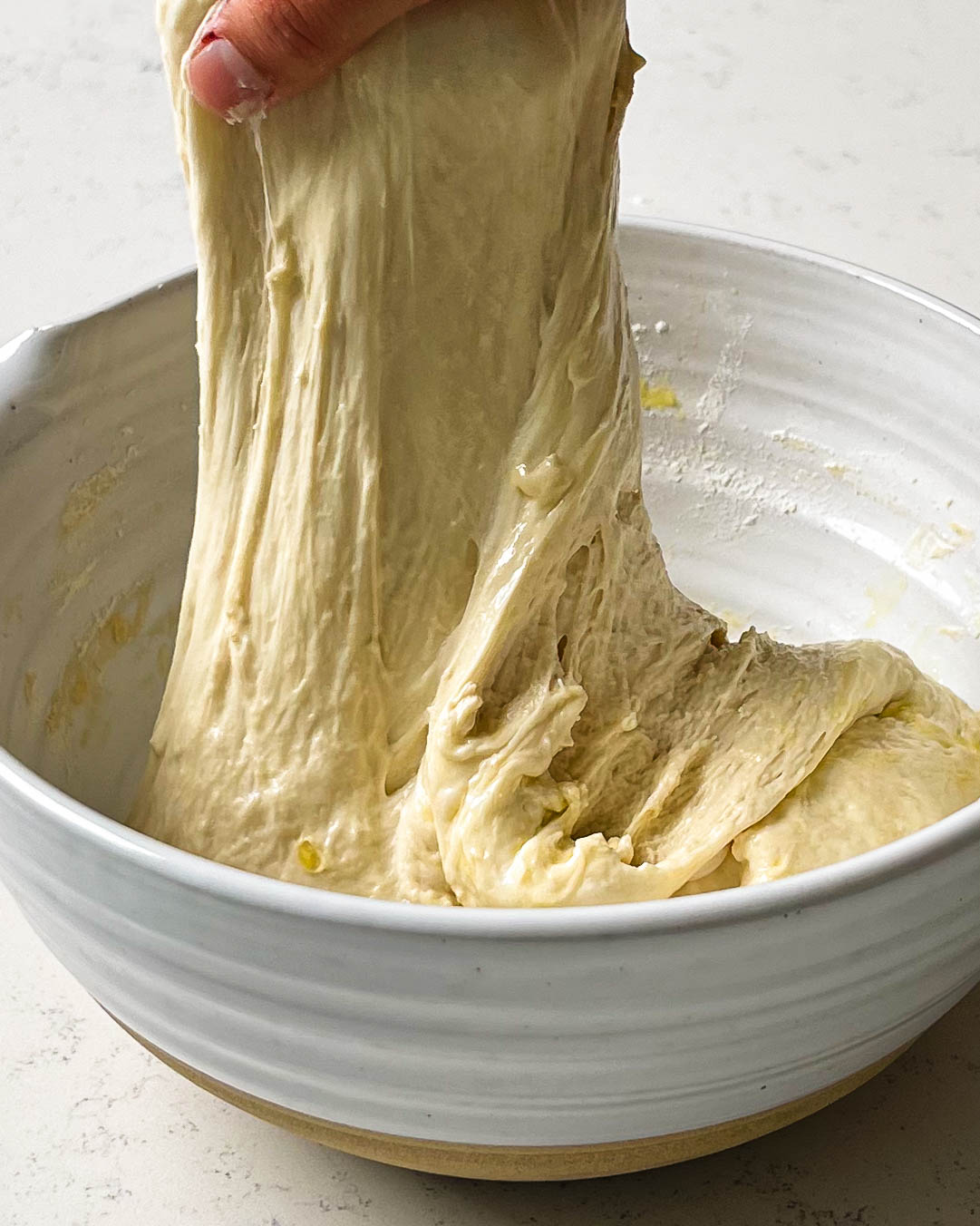 streching focaccia dough in a ceramic bowl