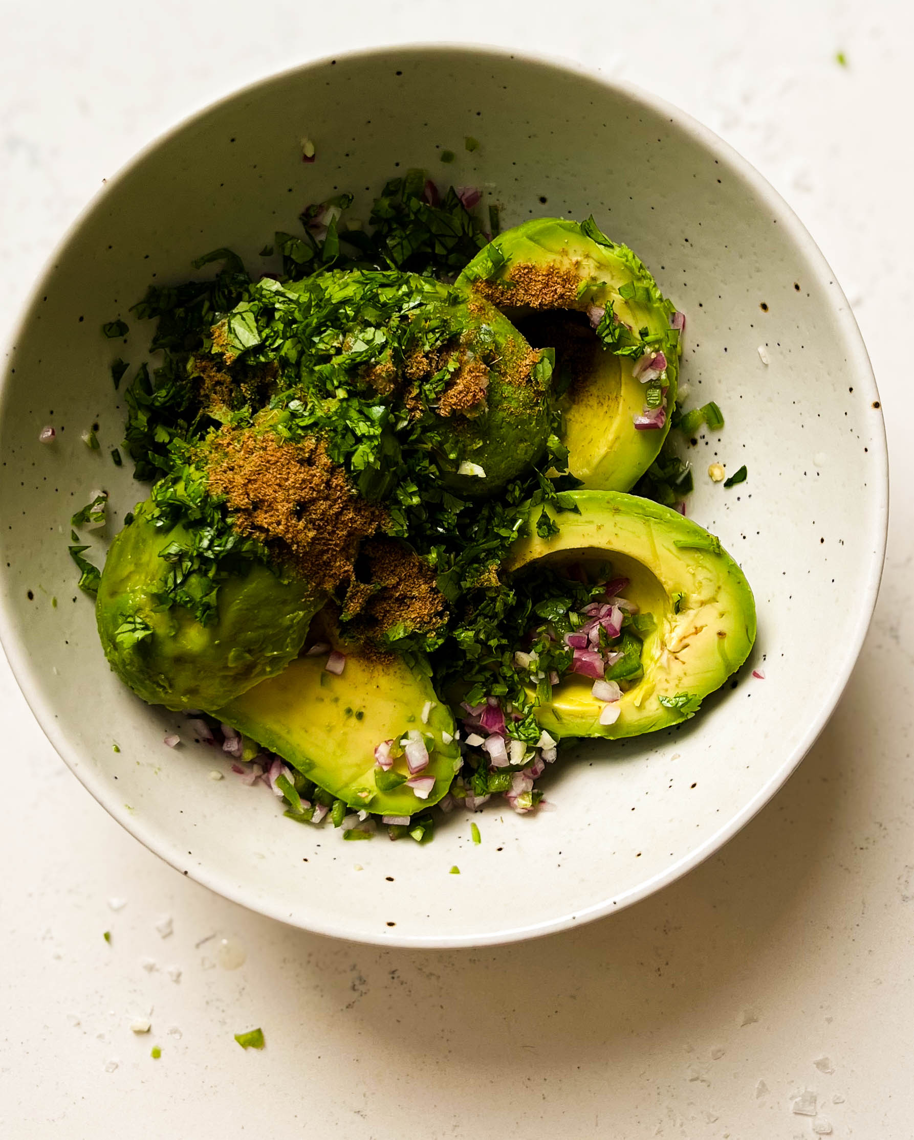 avocados in a white speckled bowl