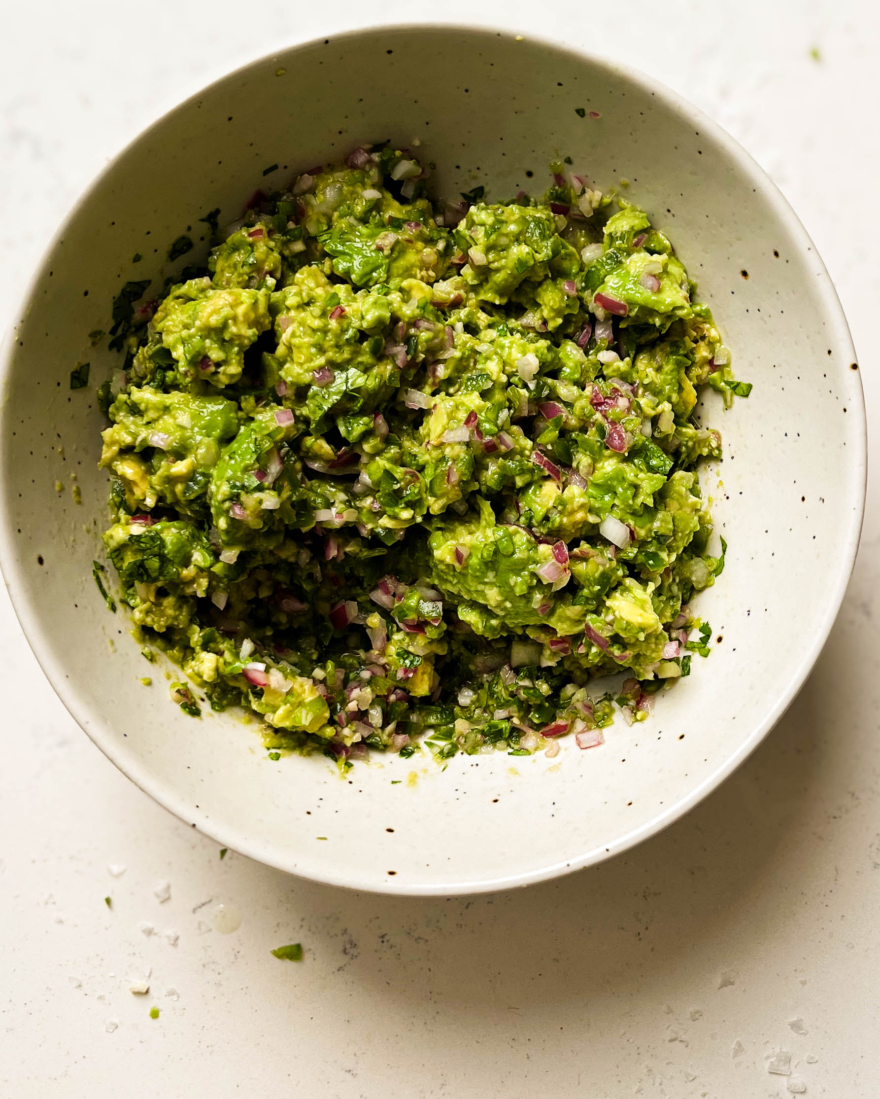 homemade guacamole in a white speckled bowl