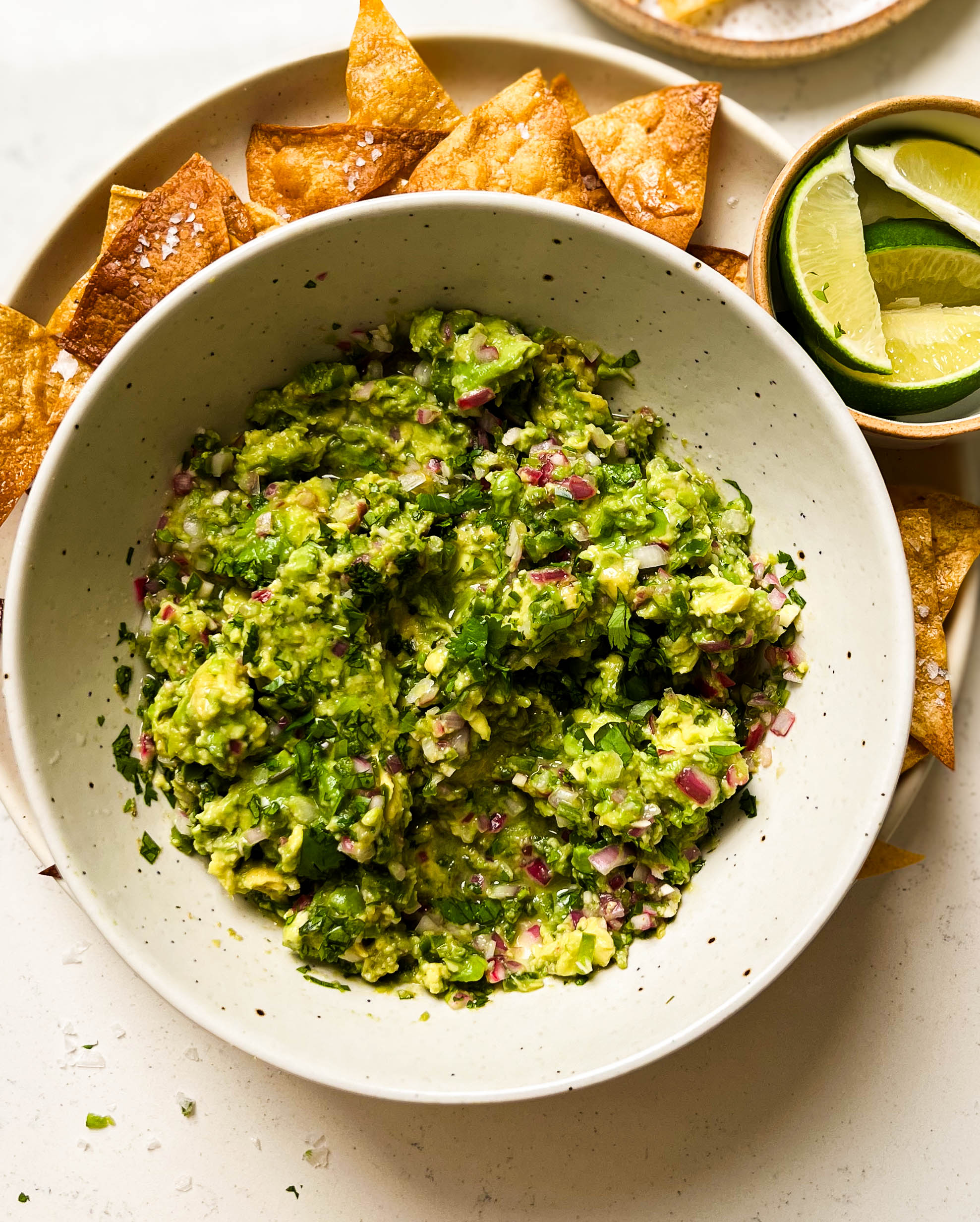 bowl of homemade guacamole on a plate of chips