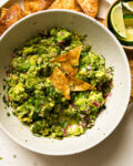 bowl of homemade guacamole on a plate of chips