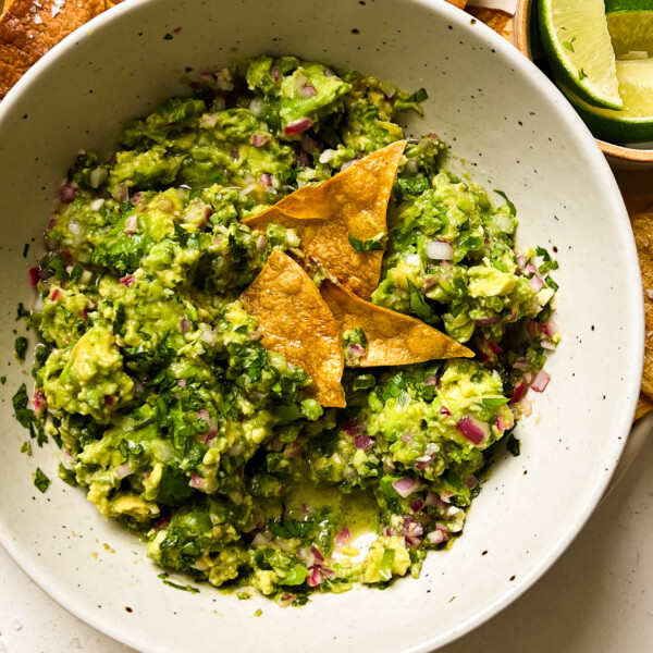 bowl of homemade guacamole on a plate of chips