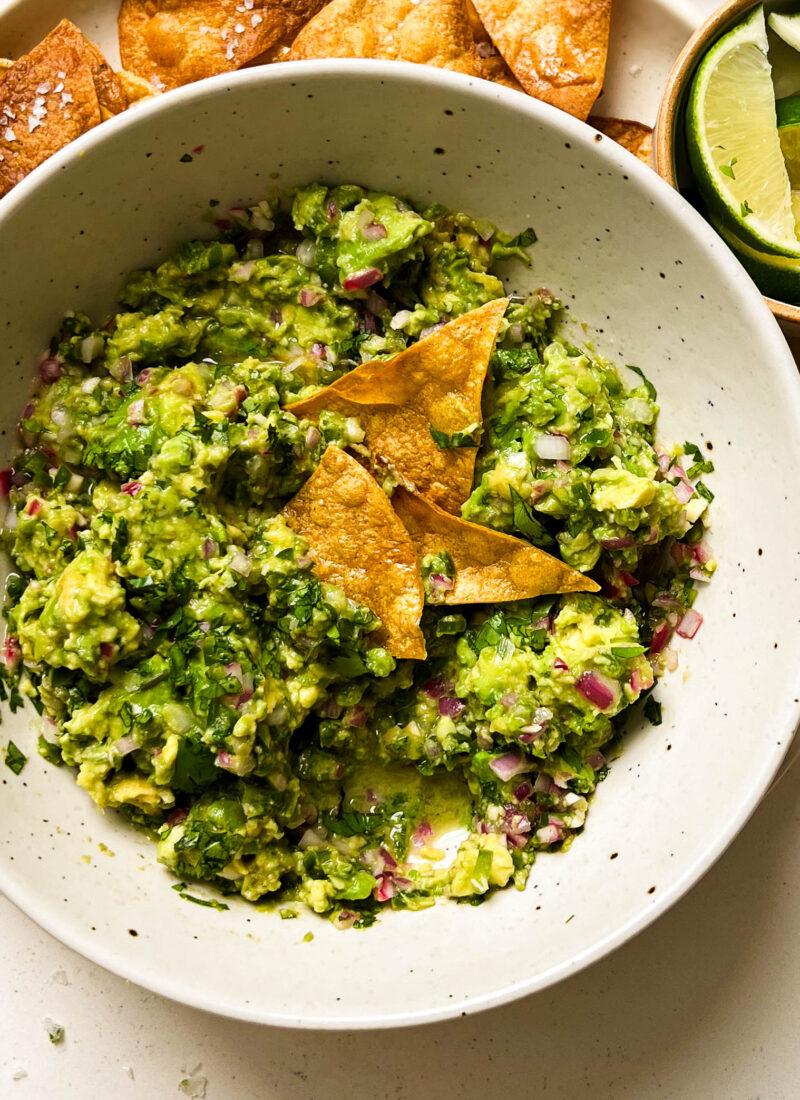 bowl of homemade guacamole on a plate of chips