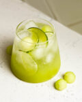 sour melon spritzer in a glass on white counter