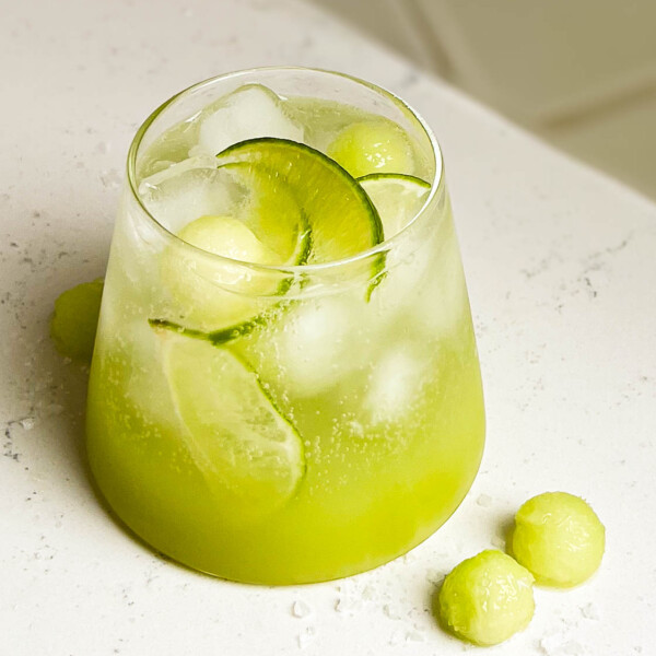 sour melon spritzer in a glass on white counter