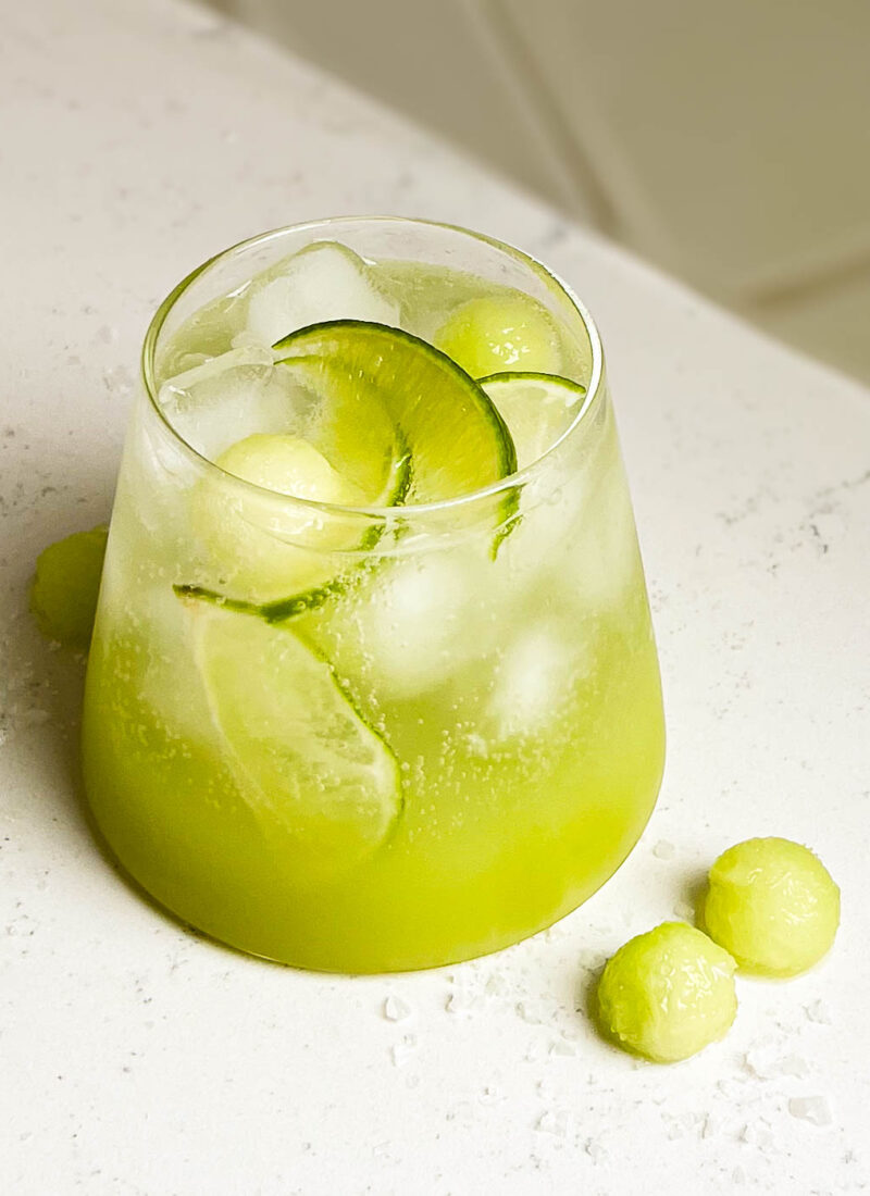 sour melon spritzer in a glass on white counter