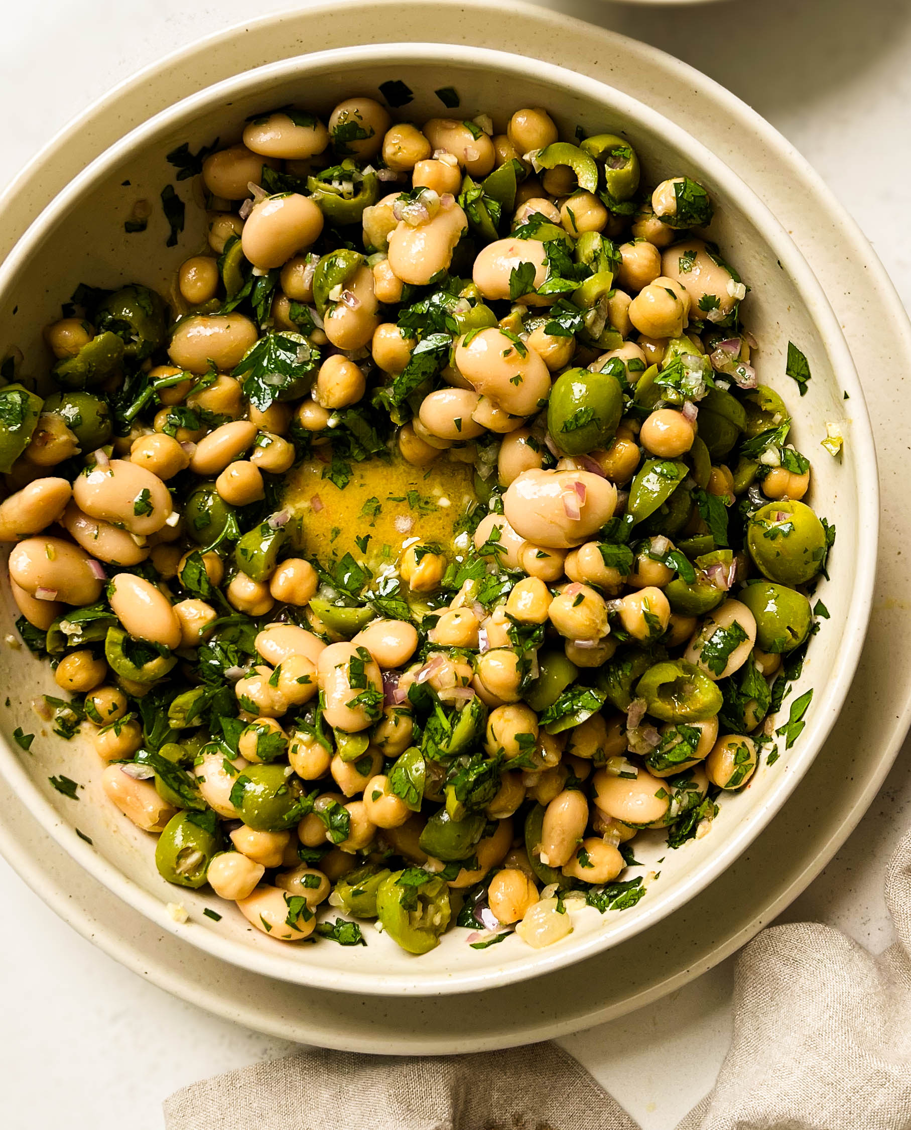 green olive bean salad in a beige bowl