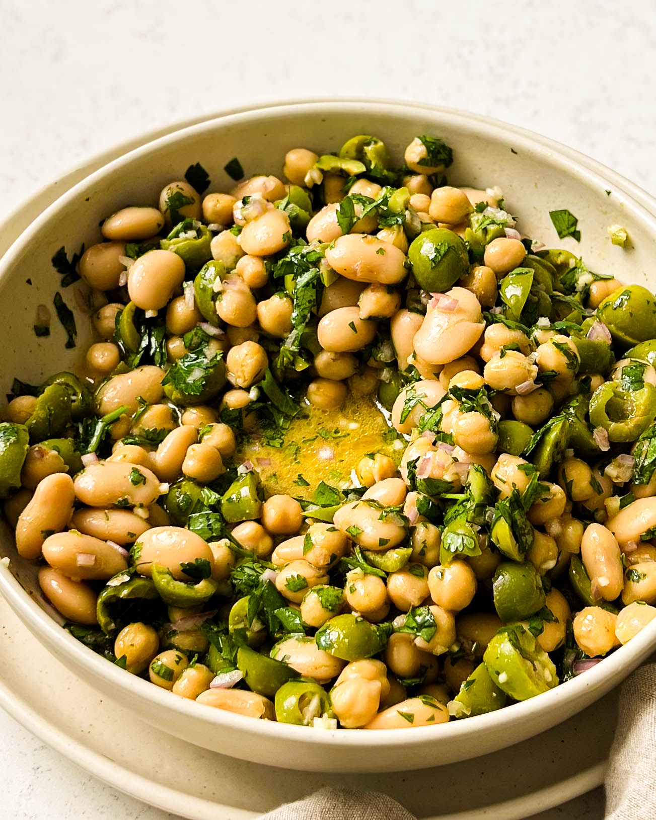 green olive bean salad in a beige bowl