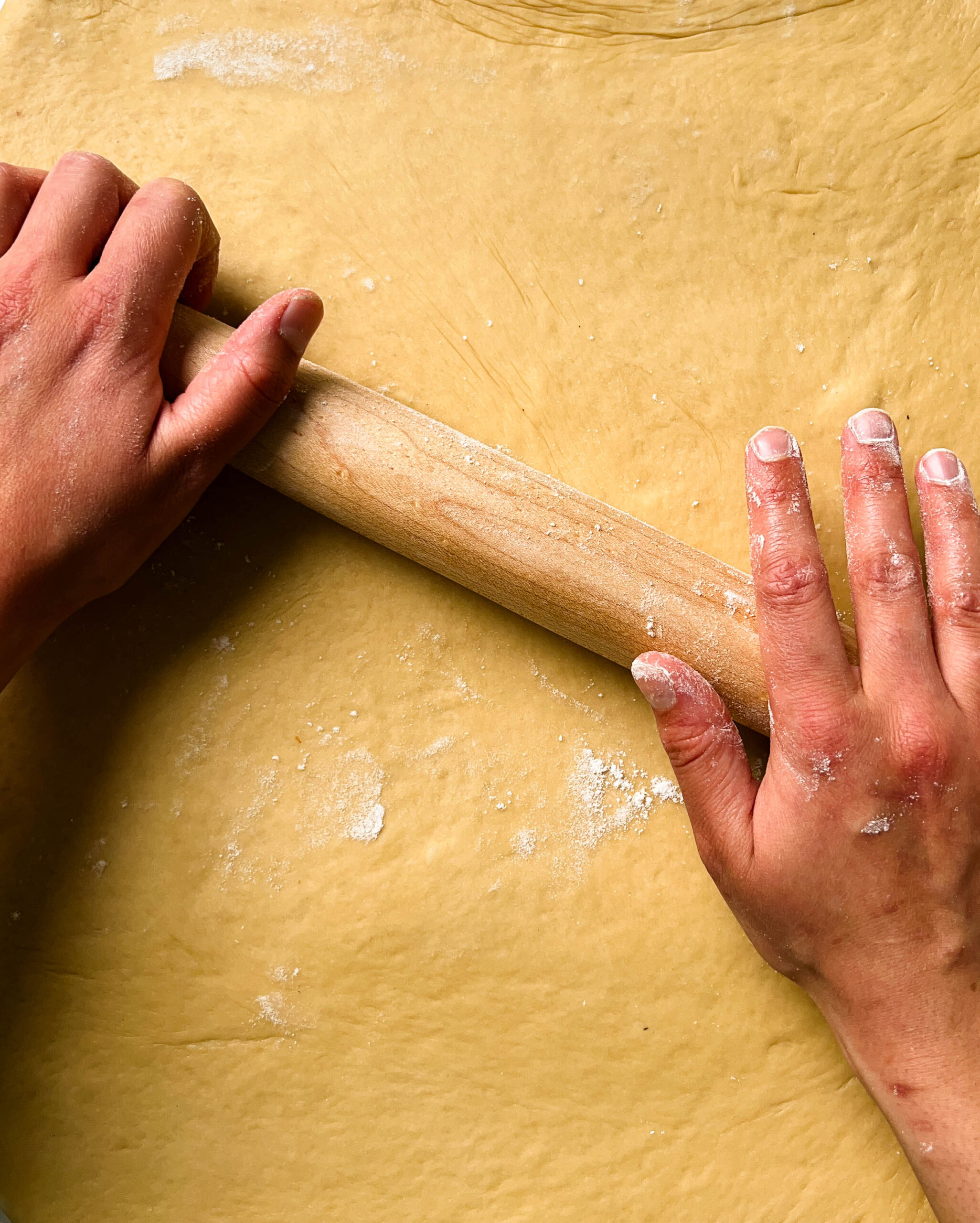 rolling dough with a wooden rolling pin