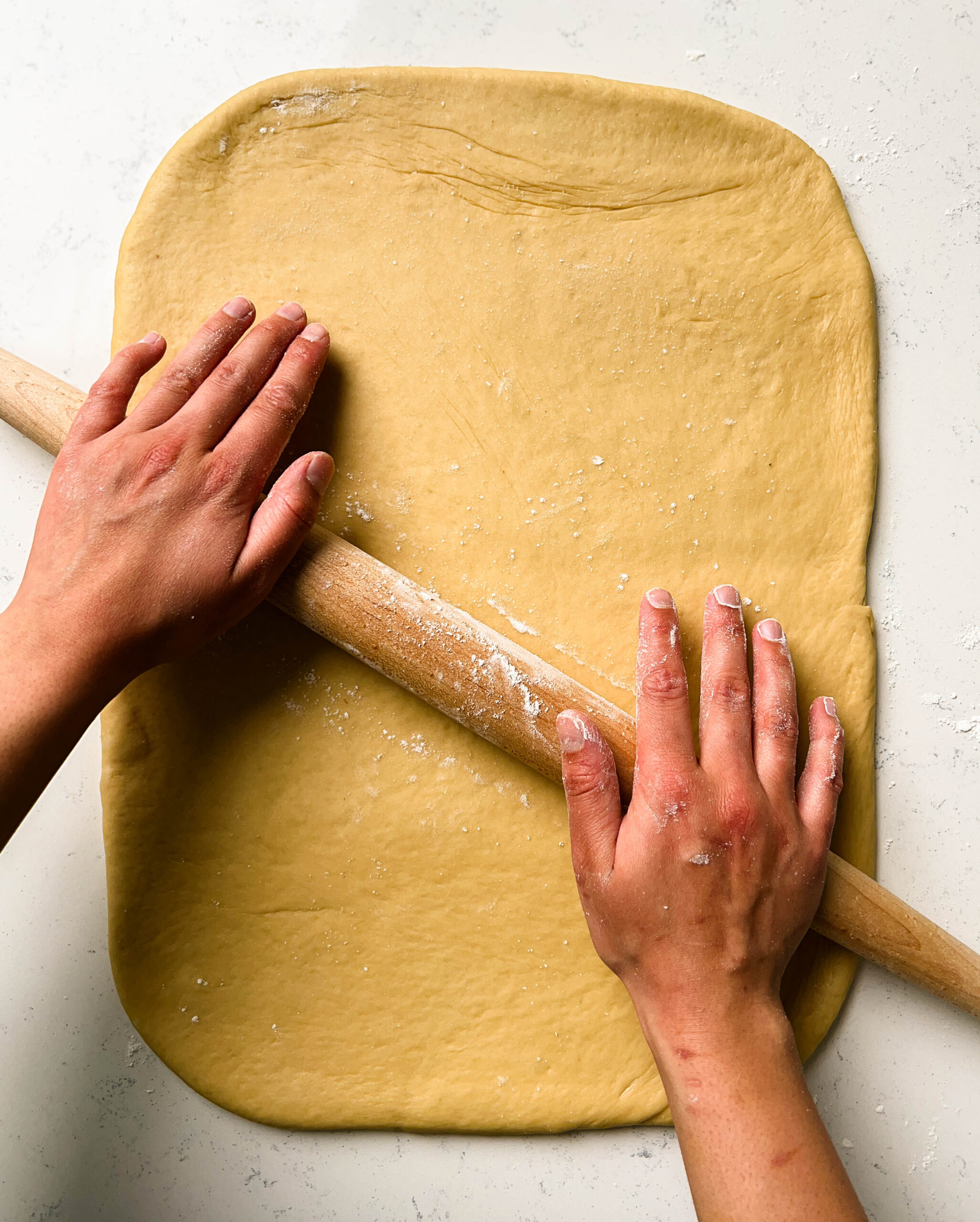 rolling dough with a wooden rolling pin