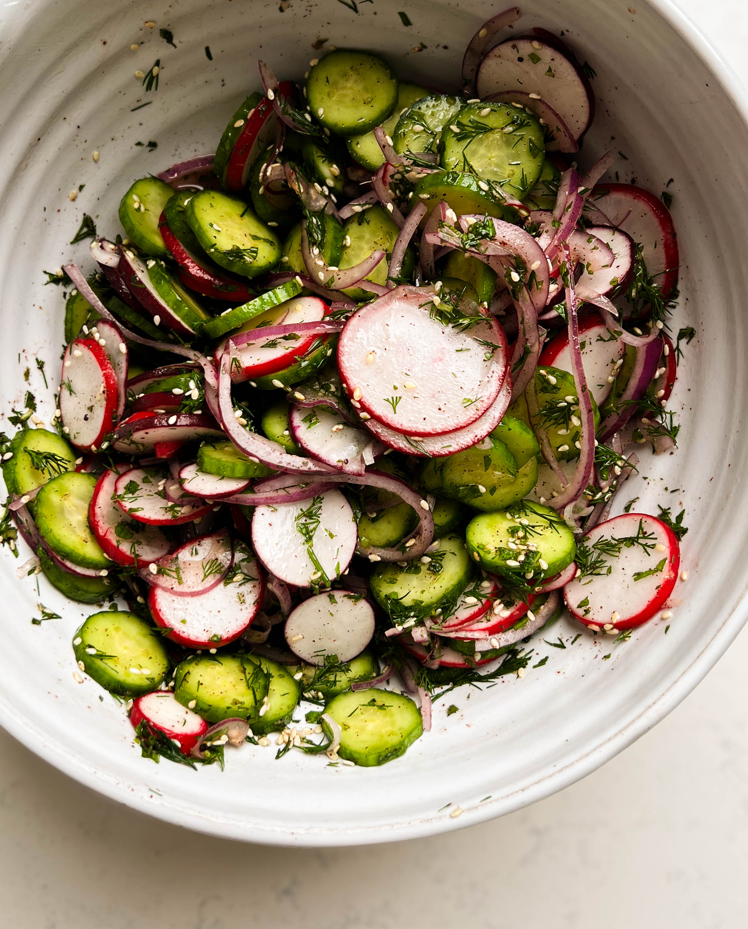 sumac cucumber radish salad in a white bowl