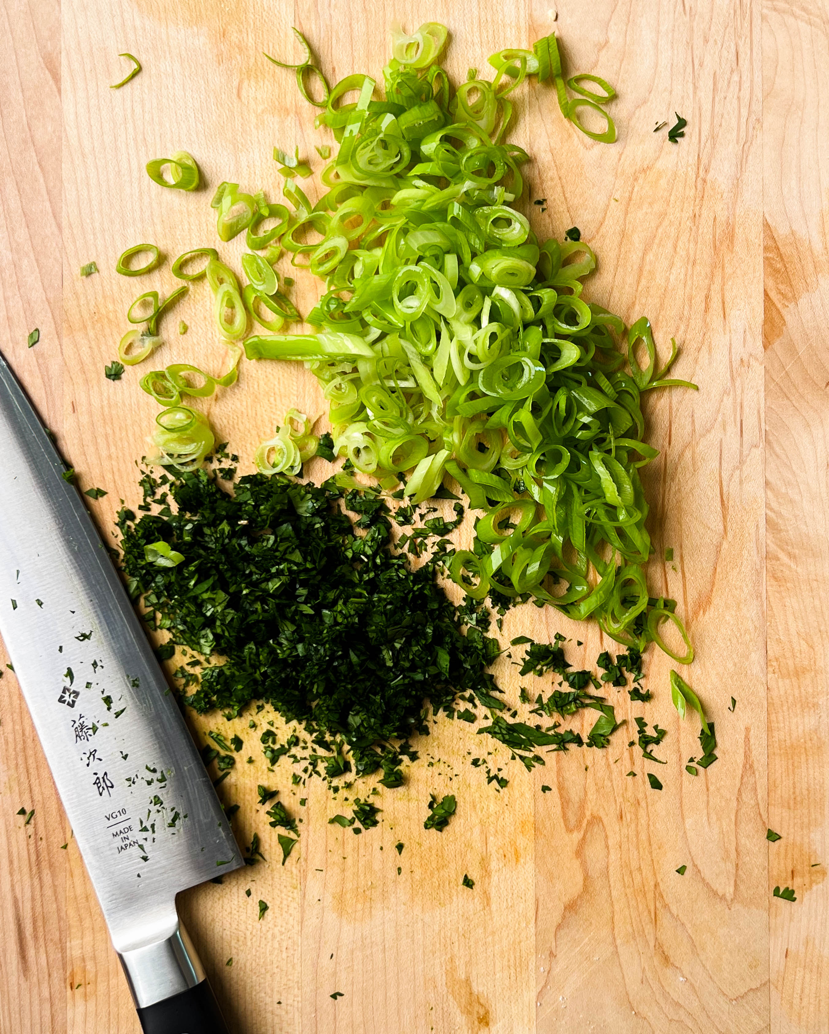 finely minced scallions and cilantro on a cutting board