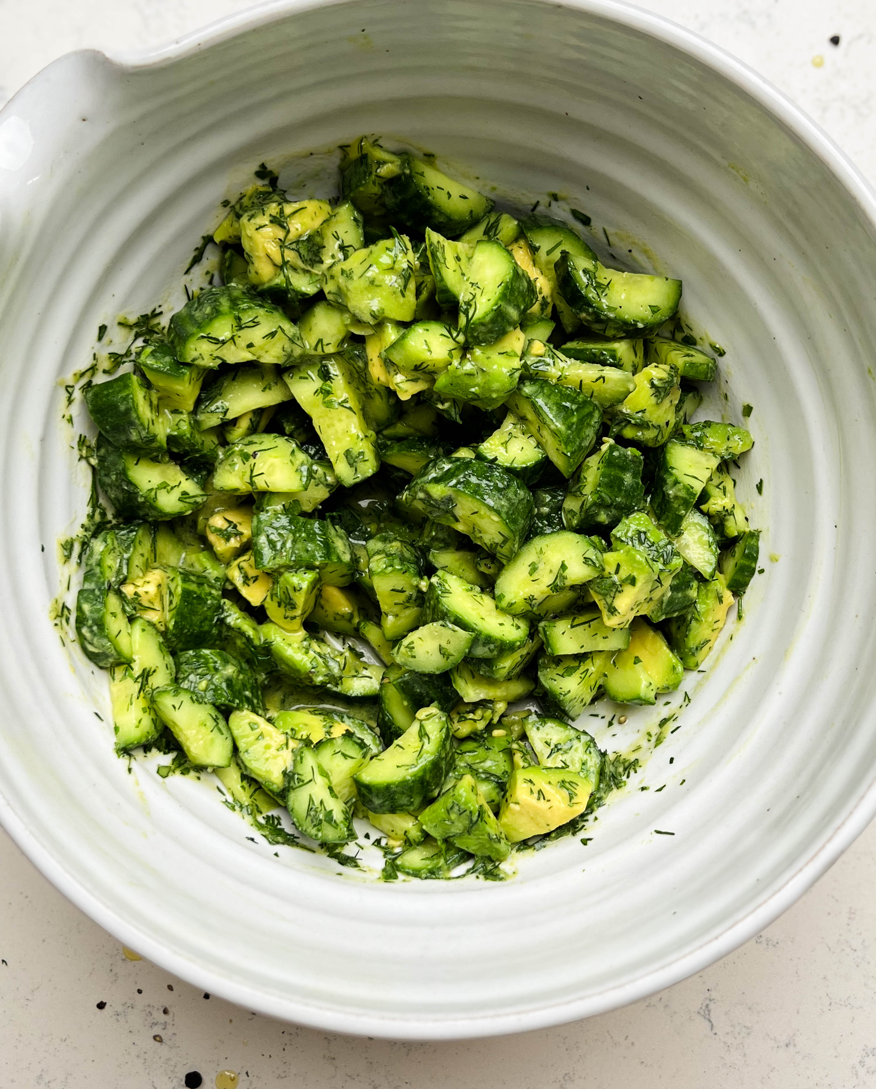 smashed cucumber avocado salad in a white bowl