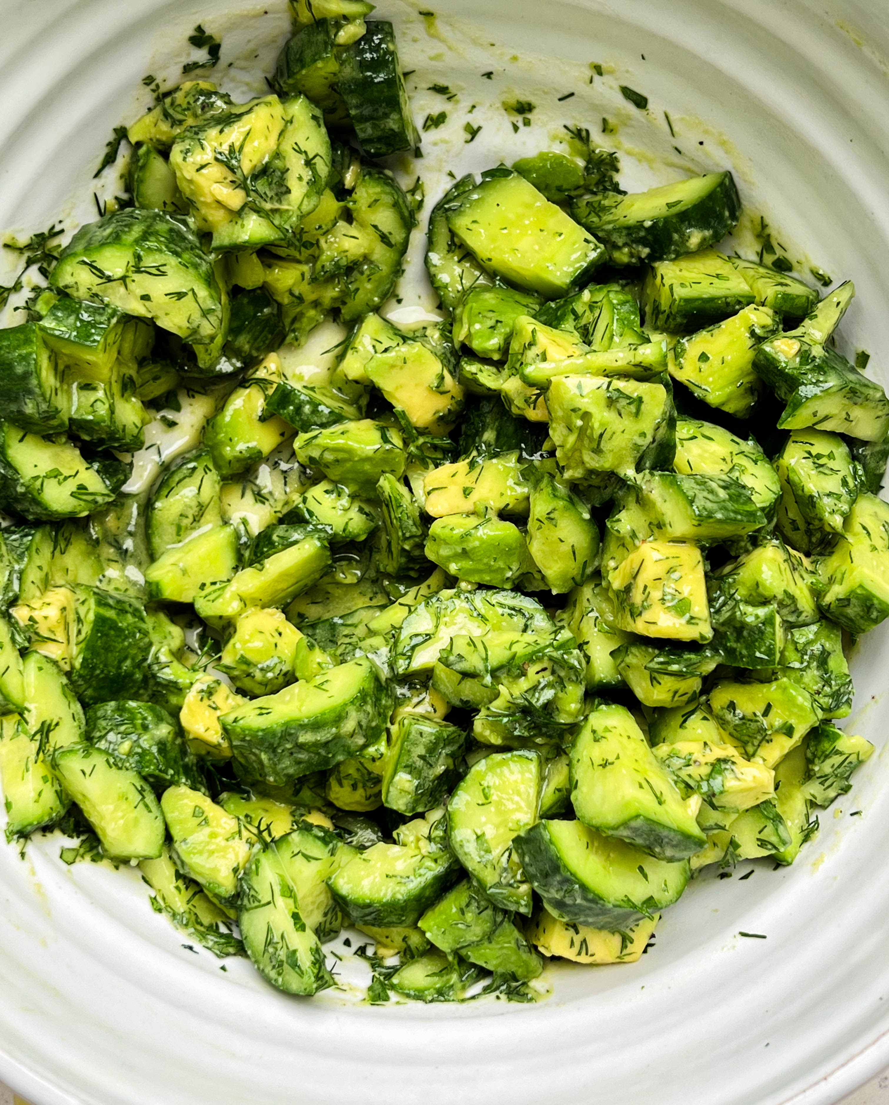 smashed cucumber avocado salad in a white bowl