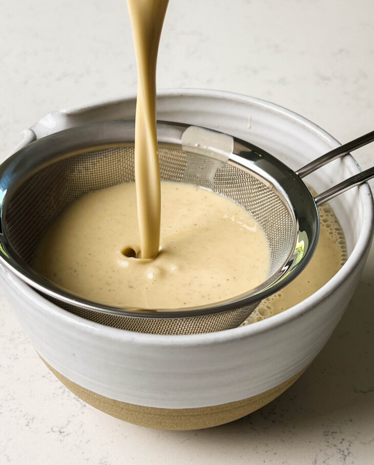vanilla bean ice cream pouring into a sieve