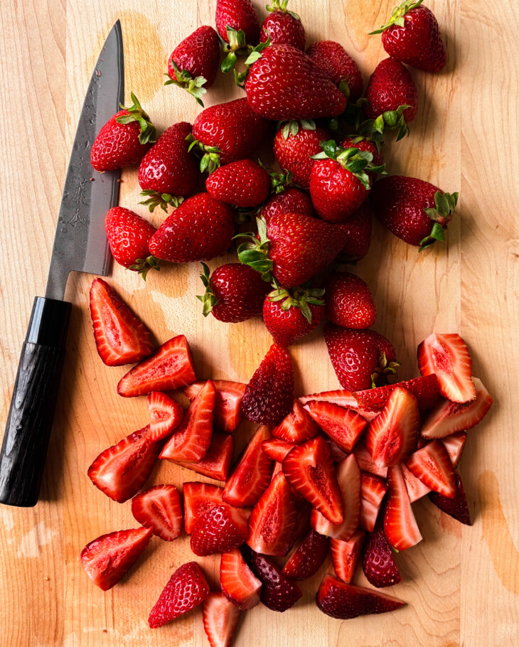 sliced strawberries on a wooden cutting board